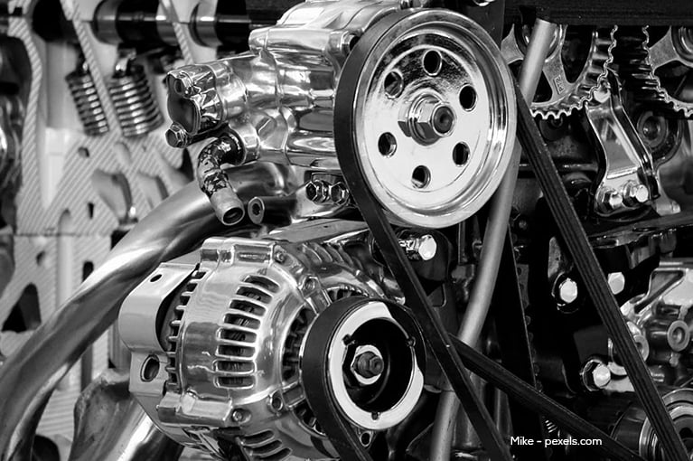 Close-up of an engine with various, shiny metal parts visible, such as a belt drive.