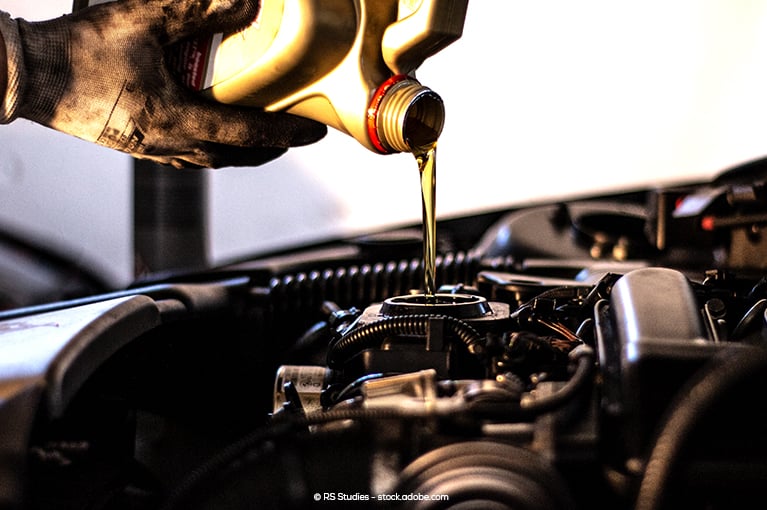 Yellow oil is poured into an engine.