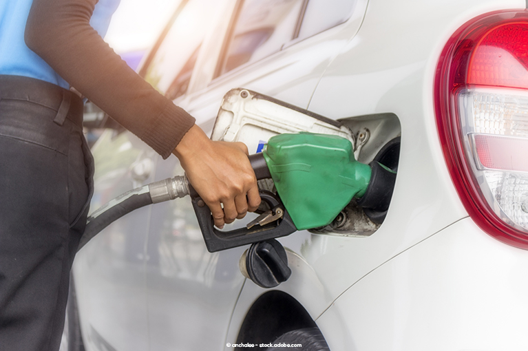 A gas station worker deposits diesel fuel into the fuel tank of a vehicle.