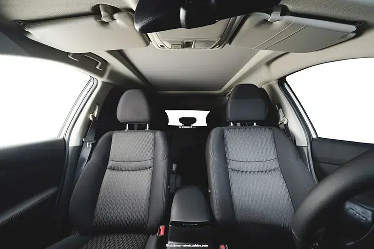 The interior of a minivan, with its front seats in the foreground. The headrests are in the center of the frame.