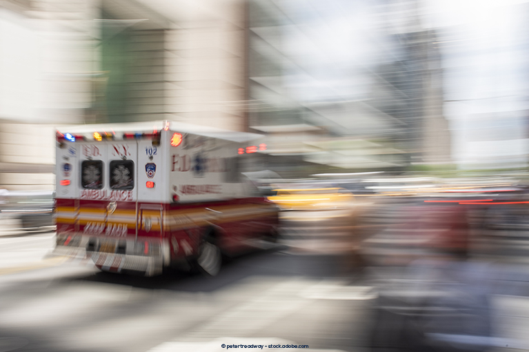 A blurry image of an ambulance vehicle rushing through traffic.