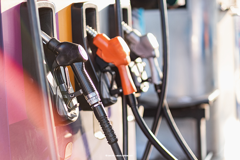 A gas station fueling spot with three pumps, one black, one orange and one grey.