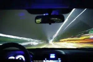 The light of streetlights, tail lights, headlights and buildings blur together in the background while the vehicle itself, from the driver's perspective, begins to shake.