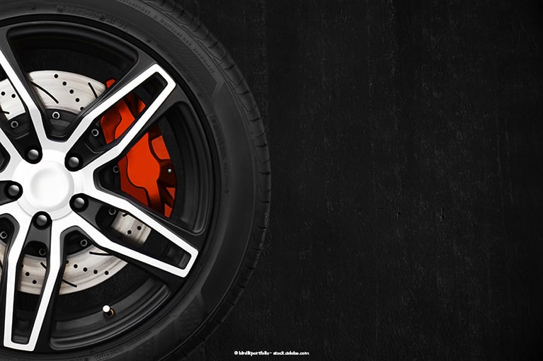 A red brake stands out inside a wheel against a black background.