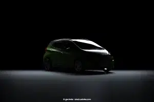 A green Chevrolet Bolt is barely illuminated by an overhead light in a nearly black room.