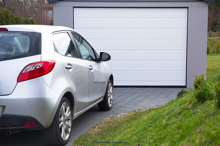 A light grey Hyundai vehicle is parked outside of a small garage.