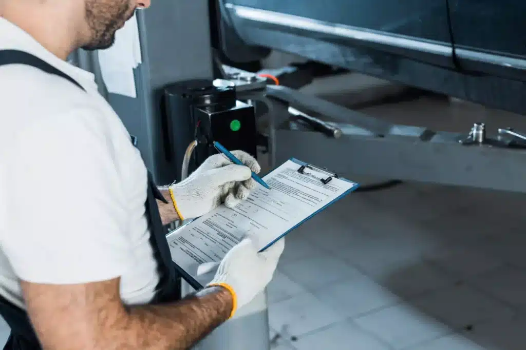 Car mechanic holding clipboard with paperwork