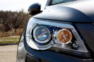 A close-up of a headlight of a black Volkswagen Tiguan. Its mirror is folded in.