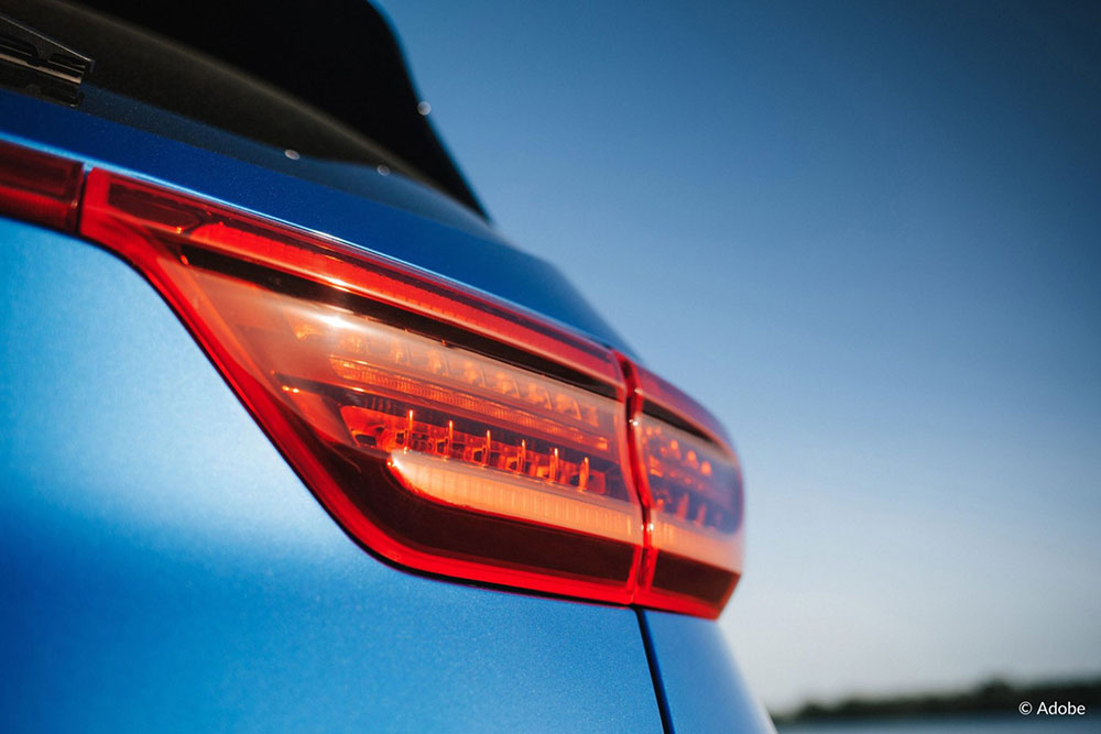 A close-up shot of a red taillight on a blue Kia vehicle.