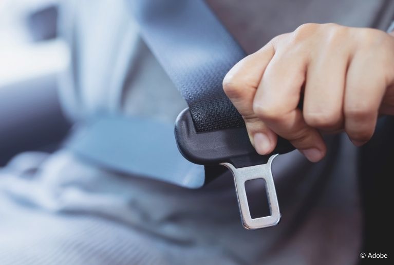 A close-up of a seatbelt being pulled by a passenger.