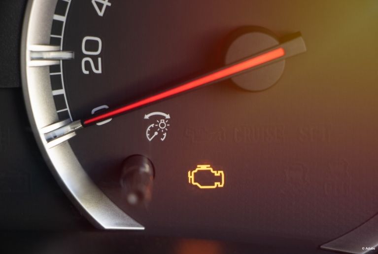 A close-up of the dashboard. The Check Engine light and a Cruise Control light are illuminated.