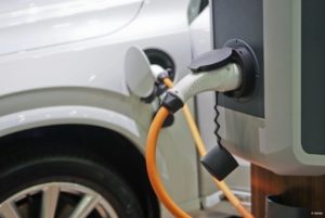 A close-up of the charging port of the white electric vehicle and the port of the charging station.