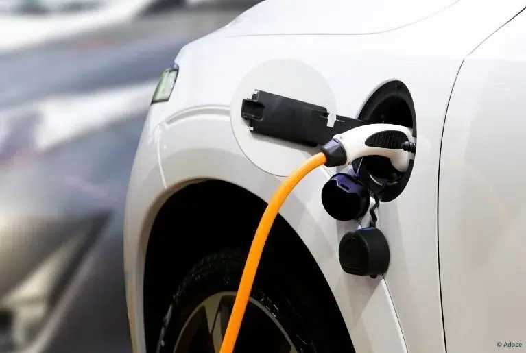 A white electric vehicle is plugged in and charging.