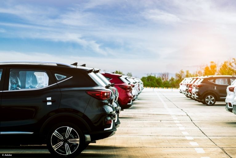 Two lines of cars parked on the roof of a parking garage.