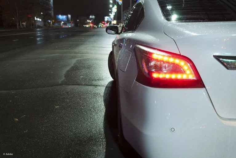 A white car has illuminated brake lights, implying that the driver has depressed the brake pedal. Many owners of 2017–2021 Nissan Altima cars have reported issues with the Automatic Emergency Braking and Forward Collision Warning systems.