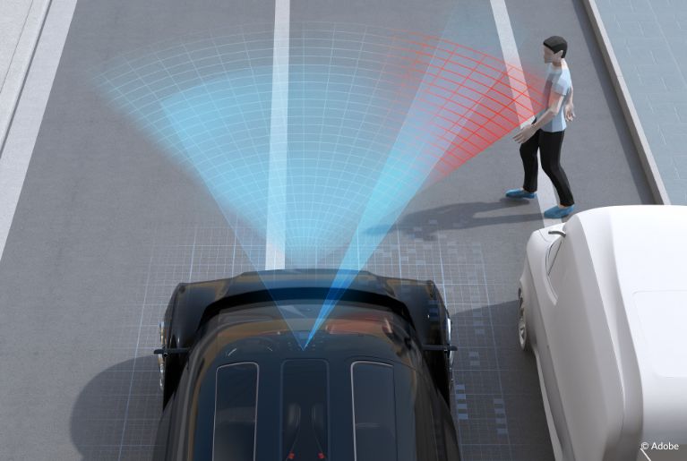 A black SUV uses radar sensors (represented by red and blue overlays) to detect a pedestrian crossing the street.