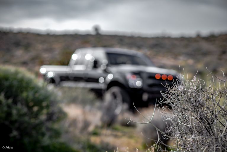 A blurry image of a pickup truck parked in the middle of a bushy desert. Nearly 215,000 model year 2016-2018 Ford F-150, 2016–2017 Ford Expedition and 2016–2017 Lincoln Navigator vehicles equipped with 3.5L EcoBoost engines. are being recalled after several crashes due to brake failures.