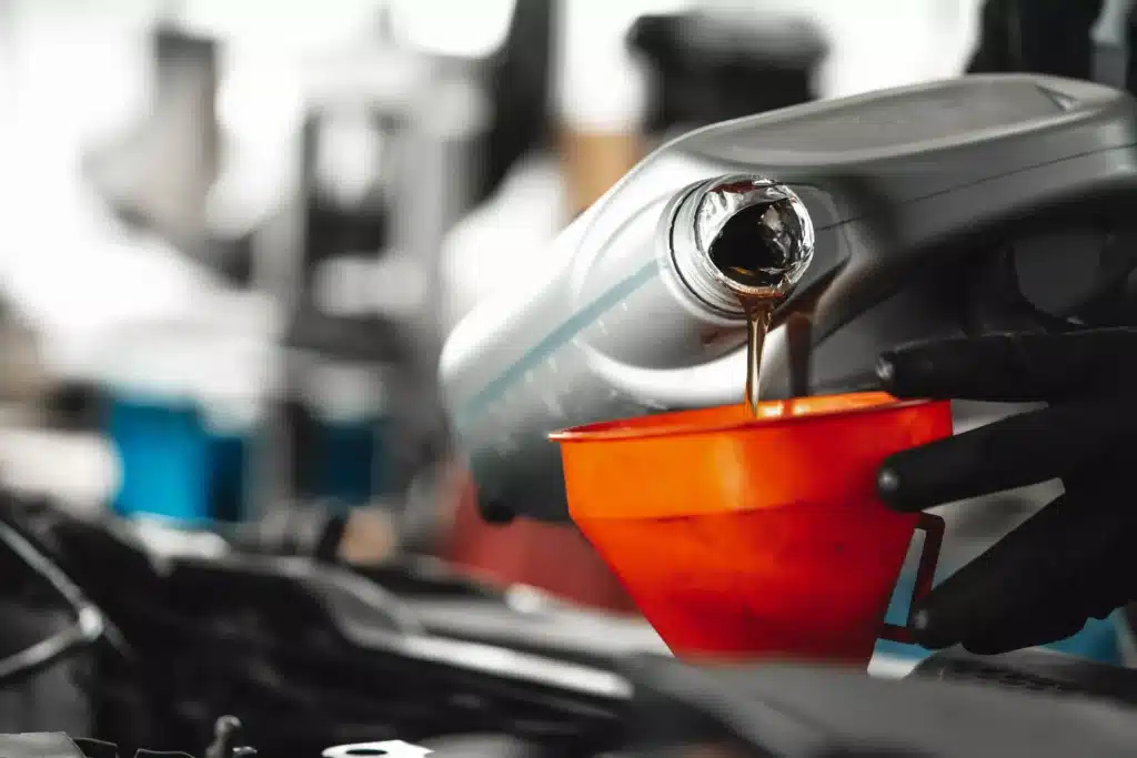 Close up of car service worker pouring engine oil