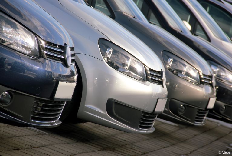 A Dutch angle shot of a line of sedans in a brick-laden parking lot.