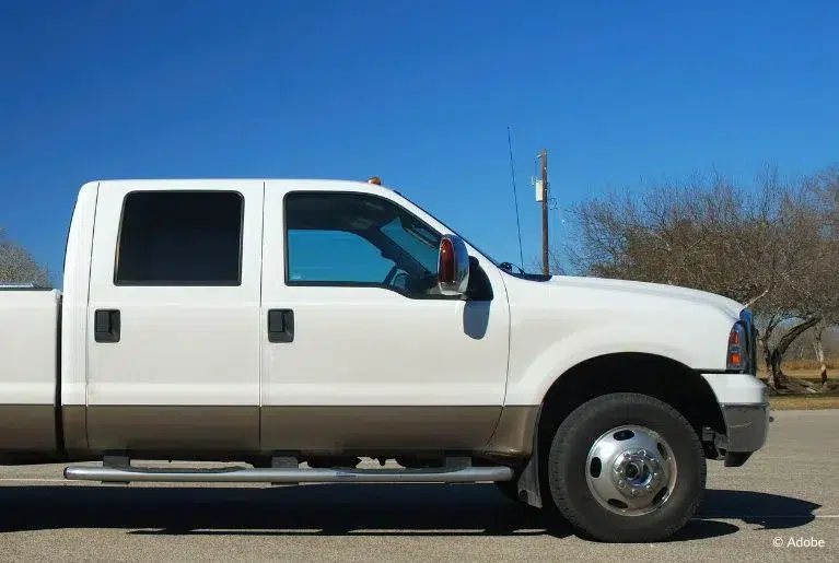 A white Ford F-150 pickup truck is parked in an empty lot.