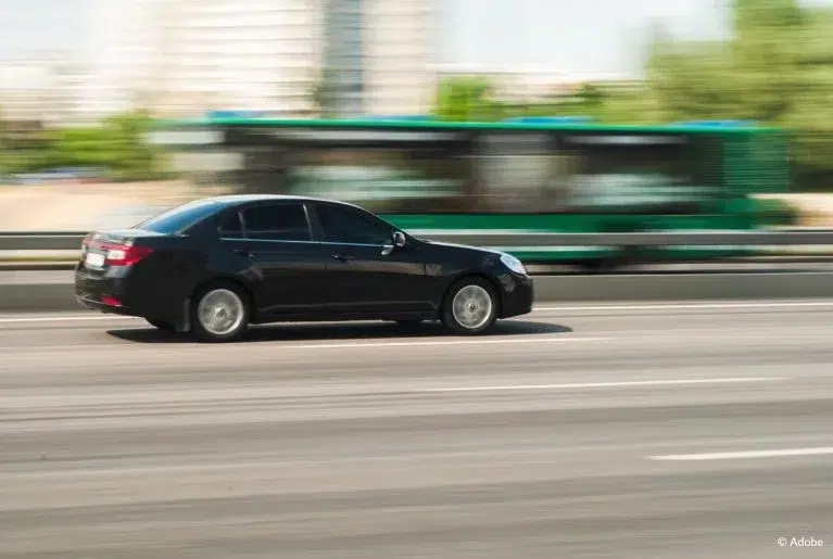 A black GM sedan speeds on an empty highway.