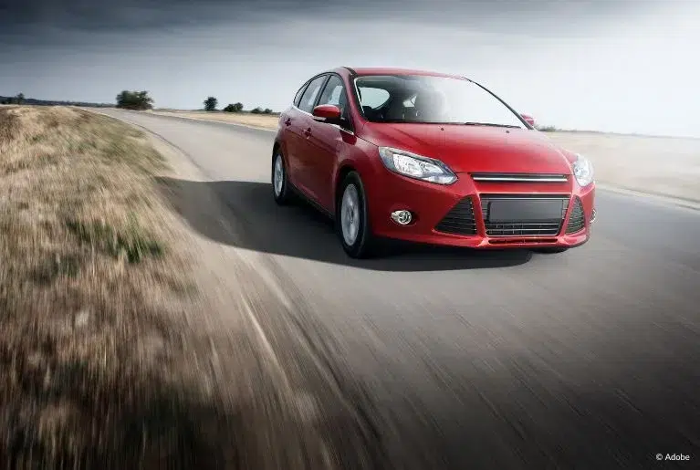 A red Ford sedan speeds on an empty road. PowerShift transmissions allegedly cause lurching, jerking and other problems in 2017–2019 Ford Fiesta and 2017–2018 Ford Focus cars.