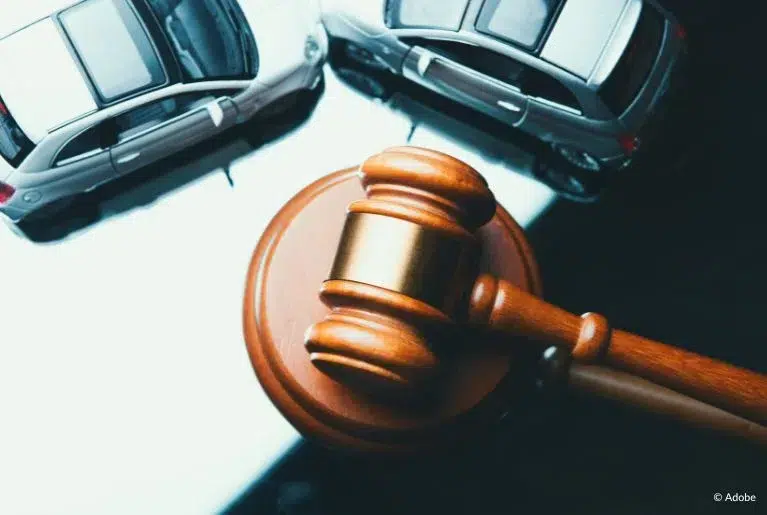 Two toy vans are placed next to a gavel resting on a table.