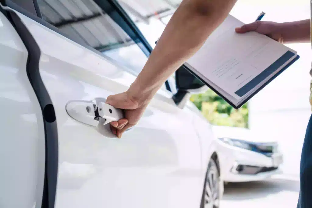 Close up of hand opening car door while holding clipboard