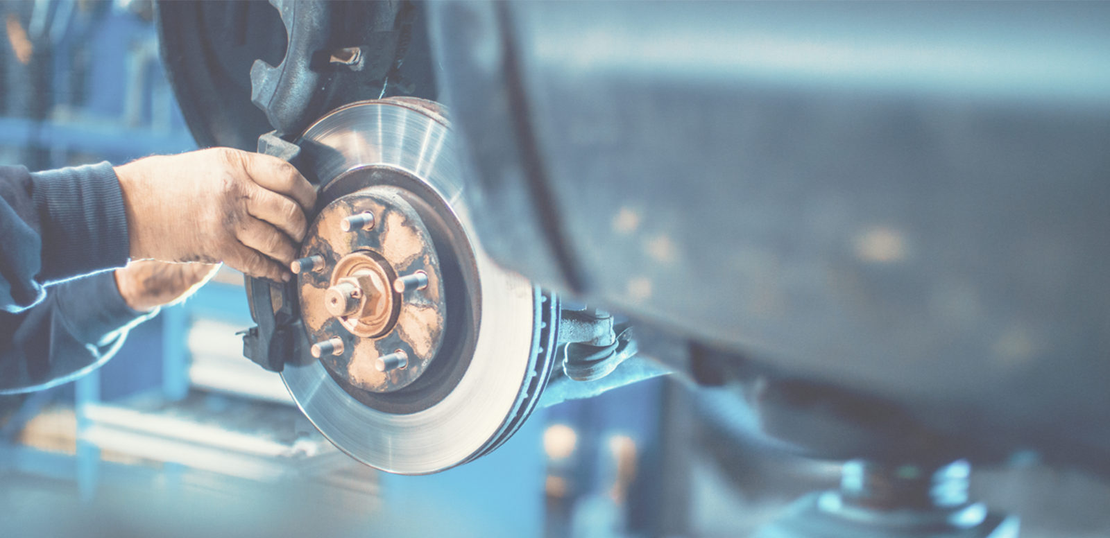 The exposed metal part of the wheel and a brake are being handled by a mechanic.