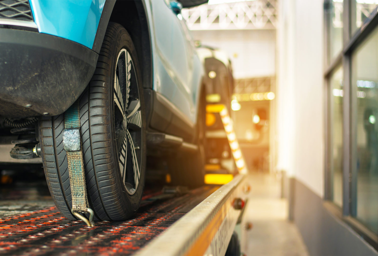 A blue car is strapped in to be towed by a tow truck.