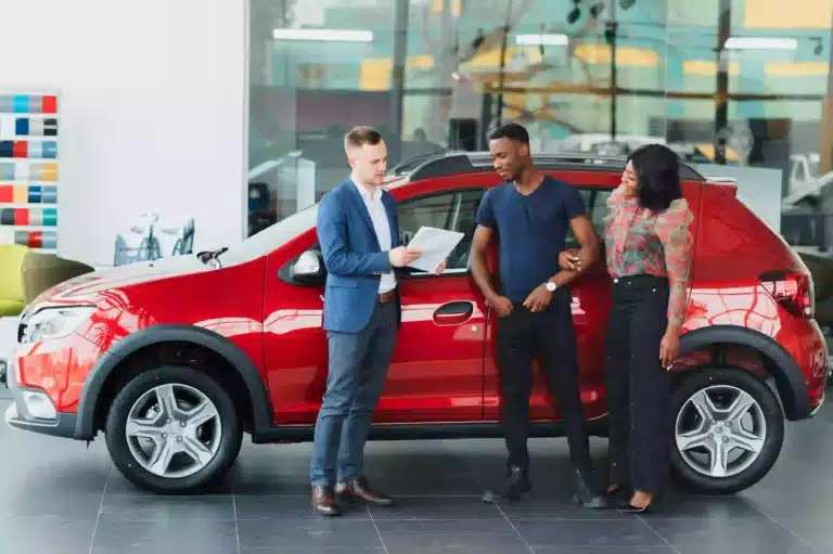 Young couple talking to salesman at dealership