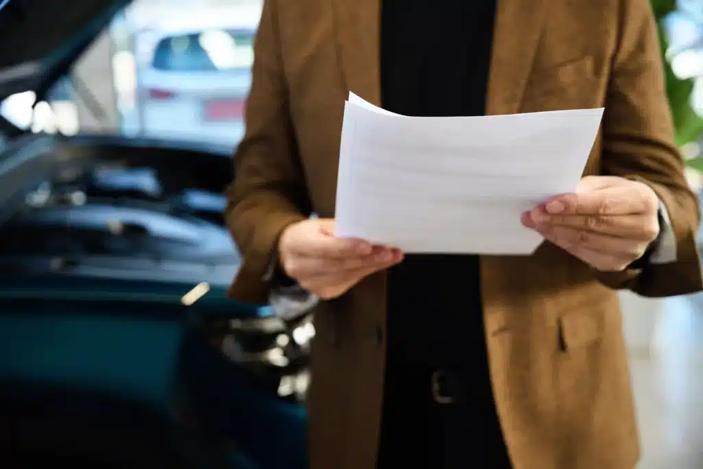 Man holding paperwork with cars blurred in the background