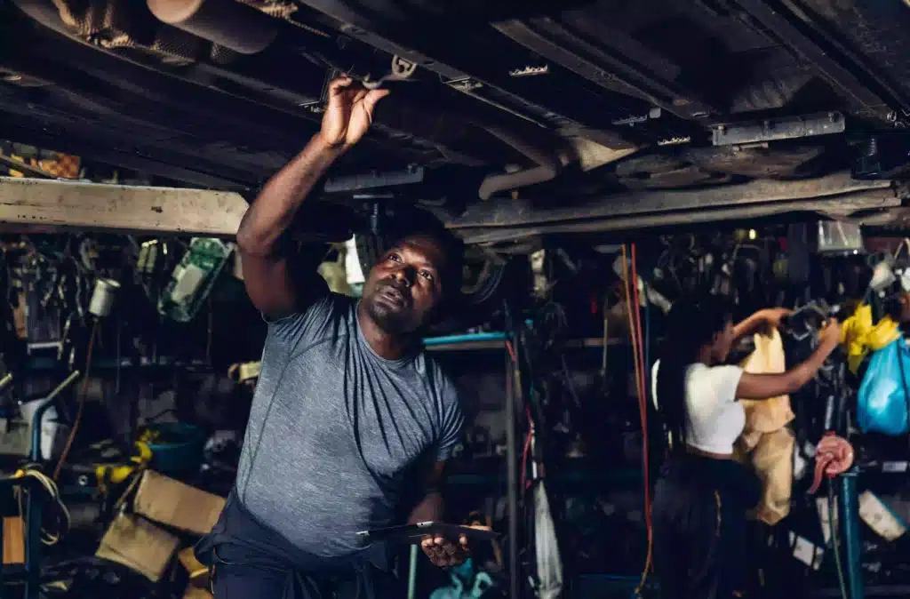 Car mechanic investigating under a vehicle raised in the air