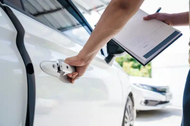 Close up of hand opening car door holding a clipboard